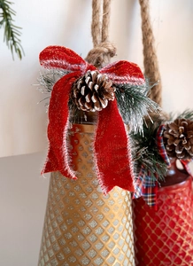 Detail of red Christmas bell ornament with velvet bow, pine cone, and rustic twine