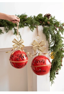 Detail of red Merry Christmas decorative balls with golden bows hanging on fireplace
