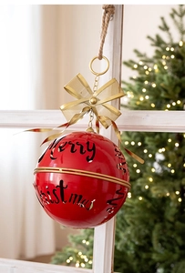 Detailed view of red metal Christmas bell with cutout Merry Christmas text and gold bow