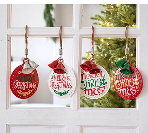 Close-up of vintage metal Merry Christmas ornaments with bells on white window frame