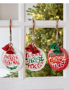 Close-up of three iron Merry Christmas door hangers with bells on a white window frame