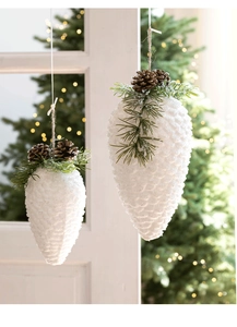 Close-up of frosted white pine cone ornaments with faux snow and pine needles