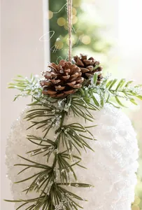 Close-up of white frosted Christmas ball with natural pine cones and rustic twine rope