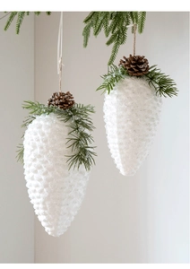 Detail of white frosted pine cone ornaments with artificial needles and small brown cones