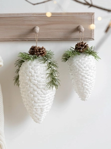 Detail of snow-dusted pine cone ornaments with needles on wooden display