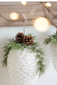 Macro detail of snowy pine cone ornament with green needles and natural wood rope