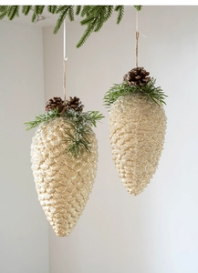 Close-up of golden glitter pine cone ornaments with pine needles and twine hangers