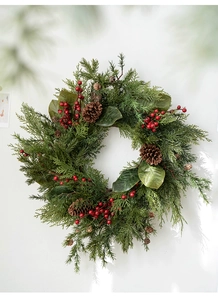 Detail of Christmas wreath with green pine needles, red berries and pine cones