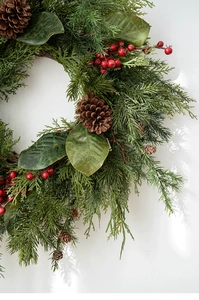 Macro detail of Christmas wreath with pine needles, red berries and natural pine cones