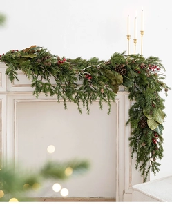 Detail view of premium Christmas pine garland with red berries and pinecones on a mantel