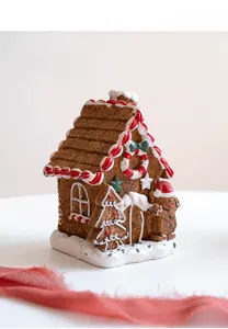 Detailed resin gingerbread house decor with candy-colored roof and festive snow base