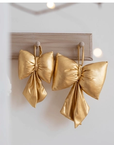 Close-up of golden metallic fabric Christmas bows hanging on a wooden wall hook