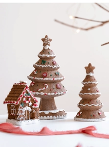 Close-up of resin gingerbread house and trees with white frosting and candy details