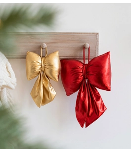 Macro detail of red and gold metallic velvet Christmas bows hanging on a wooden peg