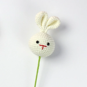 Detail of a handmade white crochet bunny decor with a green stem for flower arrangements