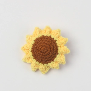 Handmade crochet sunflower accessory with yellow petals and brown center on white background