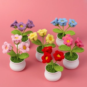 Top view of six colorful crochet lily of the valley potted plants on pink background