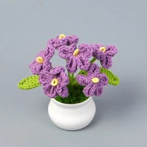 Dettaglio di fiori non ti scordar di me viola fatti all'uncinetto in vaso bianco