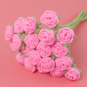 Handmade crochet pink bubble rose bouquet with green leaves on pink background
