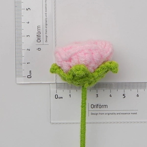 Macro view of hand-knitted bubble rose measuring 2.5cm in pink and green yarn