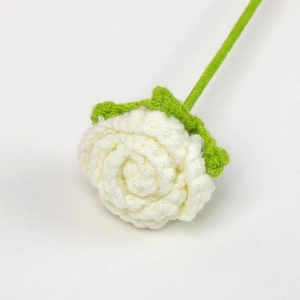 Macro shot of handcrafted white crochet rose featuring detailed petal texture and green stem
