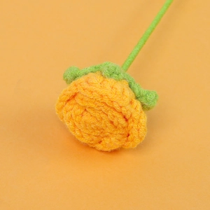 Detailed view of hand-knitted orange bubble rose with tight yarn textures and green stem