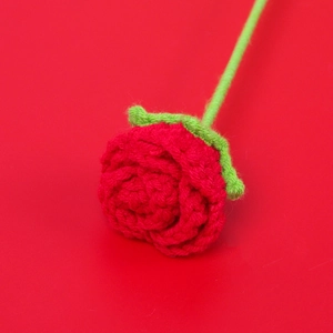 Close-up of handmade crochet red rose showing detailed yarn texture and petals