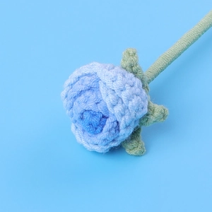 Detailed macro shot of a blue hand-knitted crochet rose with intricate petal textures