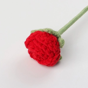 Macro detail of handmade crochet red rose with intricate knit textures and green sepals