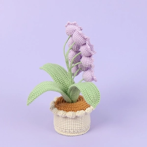 Detailed close-up of handmade crochet lily of the valley in a white knitted pot