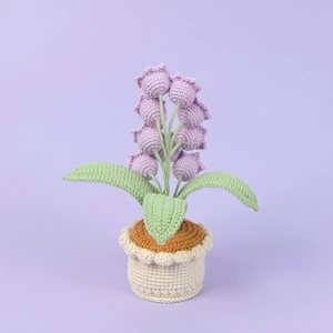 Detail of handmade crochet lily of the valley in purple with green leaves and a white pot