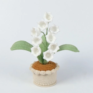 Handmade crochet lily of the valley potted plant with white bell flowers on grey background