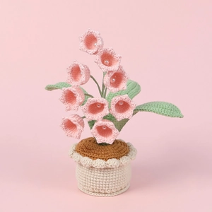 Close-up of handmade crochet lily of the valley with pink yarn petals and pearl details