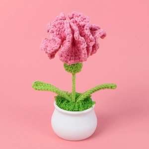 Close-up of handmade crochet pink carnation flower in a white pot for desk decoration