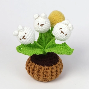 Detail view of handmade crochet potted plant with white rabbit flowers and green leaves
