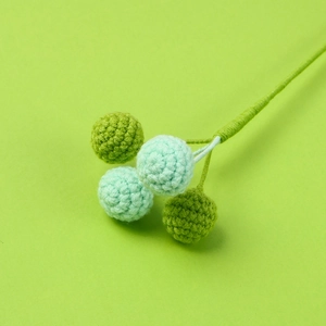 Dettaglio ravvicinato di bacche all'uncinetto fatte a mano con palline lavorate a maglia verde menta