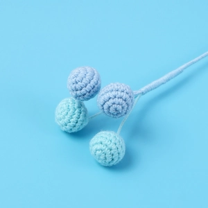 Dettaglio di rami di bacche fatti a mano all'uncinetto con filato morbido e trame blu