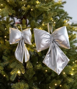 Shiny silver fabric bows with metallic coating hanging on a festive Christmas tree decoration