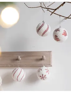 Detailed view of 8cm white foam Christmas balls with red glitter patterns on tree branches