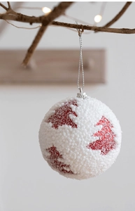 Detail of white snowy Christmas ball with red glitter tree pattern on branches
