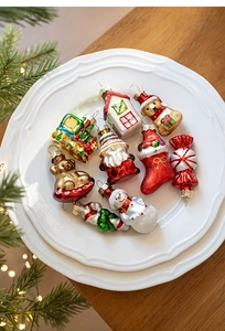 Close-up of glass Christmas ornaments with snowman, gingerbread house, and festive train