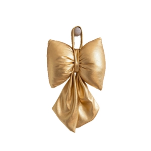 Golden shiny fabric Christmas bow ornament hanging on a wooden hook for holiday decoration