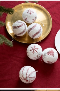 Detail of 8cm white flocked Christmas ball with red glitter snowflake and silver string