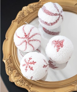 Detail of white flocked Christmas balls with red glitter snowflakes on a gold mirror tray