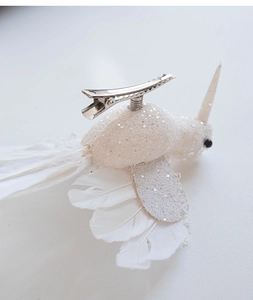 Dettaglio macro della molletta per capelli a forma di uccello bianco con piume e glitter
