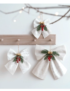 Detailed view of white velvet Christmas bows with gold bells and red berries decor