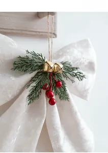 Close-up of velvet Christmas bow featuring green pine needles, red berries and golden bells