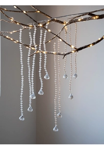 Close-up of clear acrylic bead chains with teardrop pendants on branches with warm lights