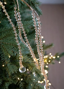 Detail of crystal acrylic garland with teardrop pendant on a lighted Christmas tree