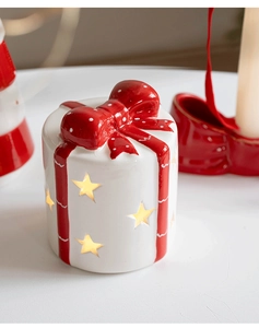 Nahaufnahme der Keramik-Weihnachtsdeko in Geschenkform mit Sternen und warmem Licht